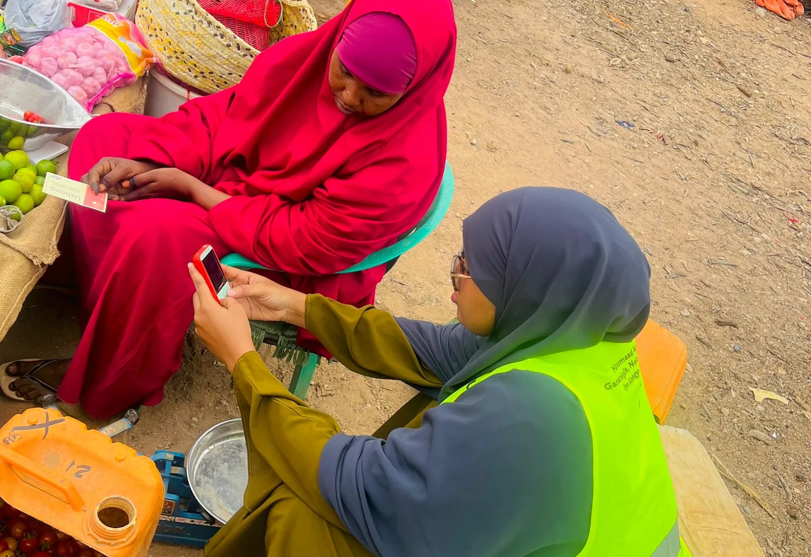 A Sauti field officer demonstrates a mobile service on a feature phone to a market trader in Somalia.
